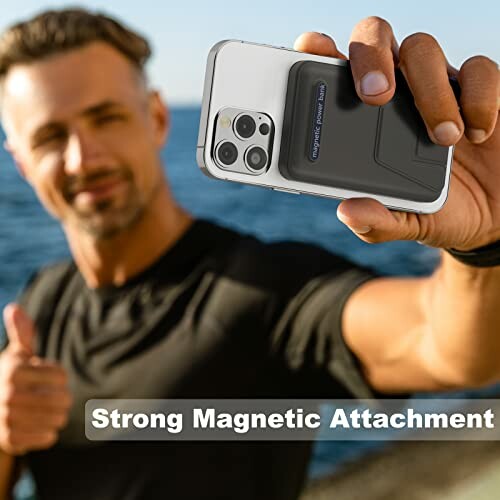 Man holding phone with magnetic case by the sea.
