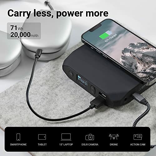 Portable power bank charging a smartphone with headphones nearby.